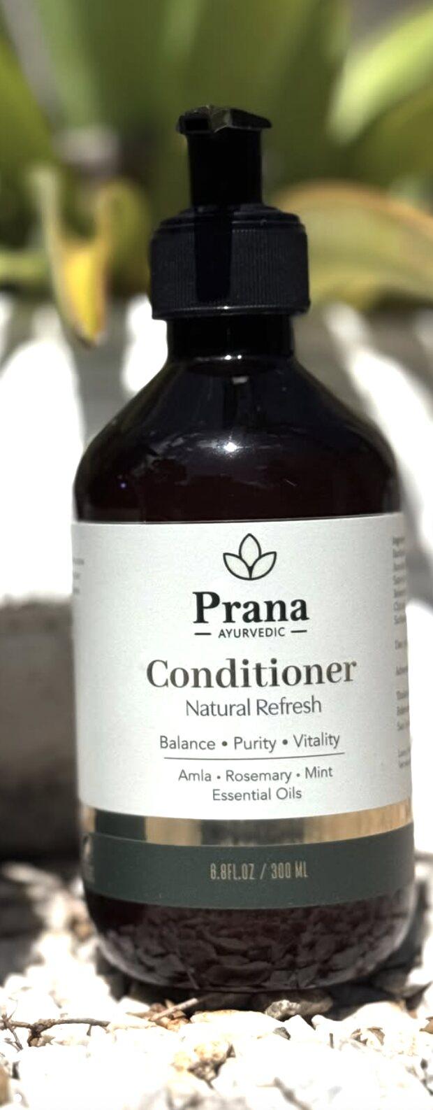 Botella de acondicionador Prana Natural Refresh sobre piedras blancas