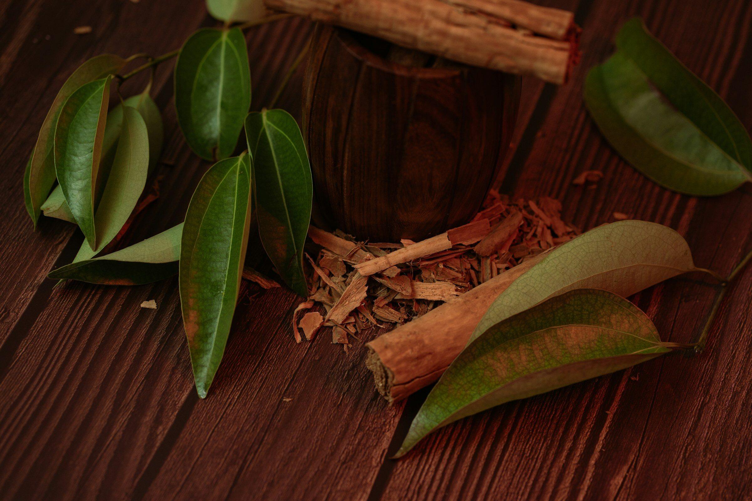 Ramas de canela y hojas de laurel sobre una mesa de madera oscura