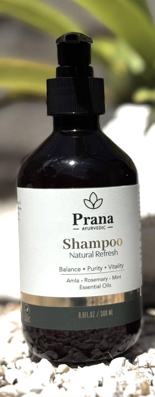 Botella de shampoo Prana Natural Refresh sobre piedras blancas